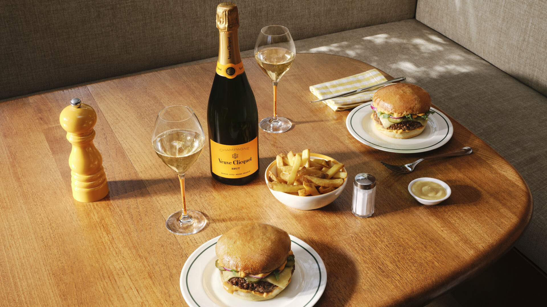 Bottle of Veuve Clicquot Brut Yellow Label with two glasses, a burger and french fries