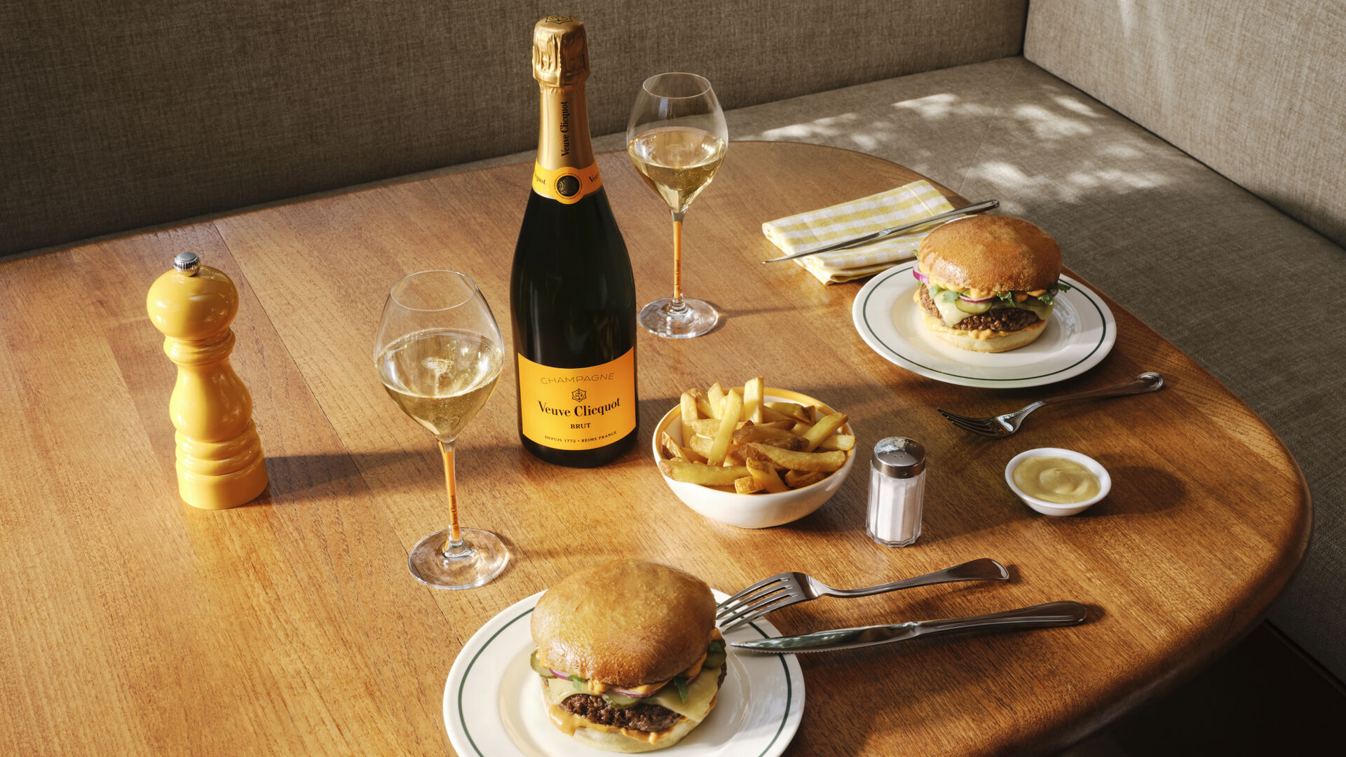 Bottle of Veuve Clicquot Brut Yellow Label with two glasses, a burger and french fries