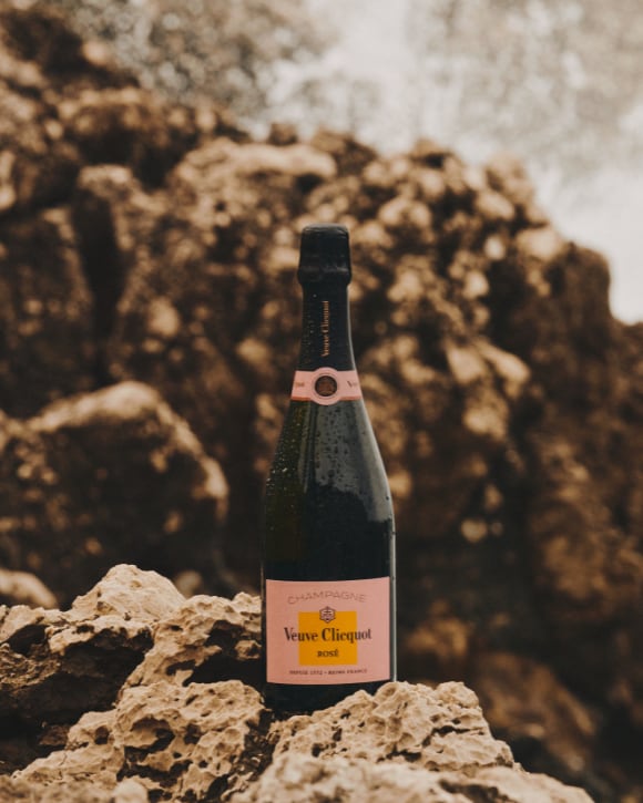 Rose champagne bottle on a rock in front of the sea