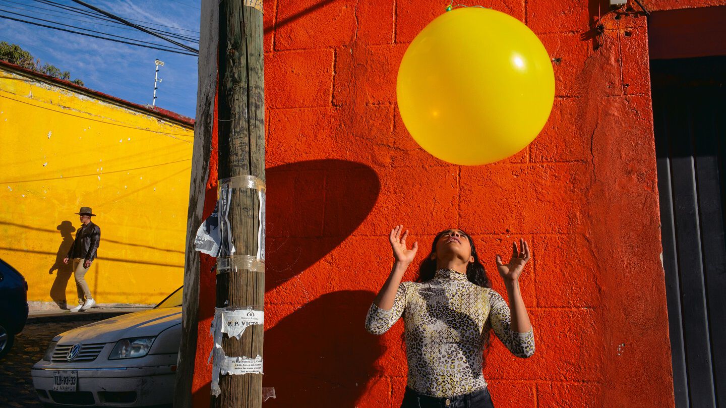Alex Webb photo of a woman with a yellow balloon in front of a red wall Alex Webb photo of a woman with a yellow balloon in front of a red wall