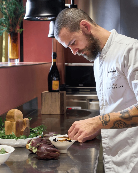 Mattia Trabetti preparing a dish with a bottle of La Grande Dame Rosée 2015