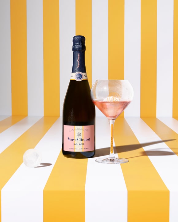 Bouteille de champagne RICH Rosé avec une coupe pleine et un glaçon sphérique