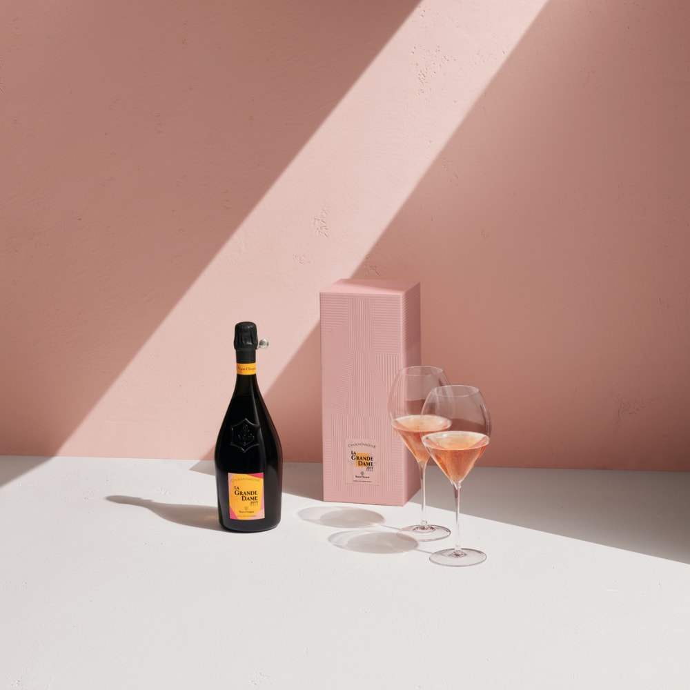 Bottle of La Grande Dame Rosé 2015 with two full glasses and its giftbox Bottle of La Grande Dame Rosé 2015 with two full glasses and its giftbox