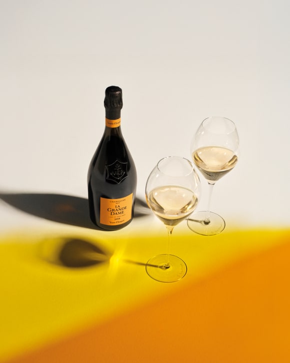 Bottle of La Grande Dame 2018 with two full glasses of champagne