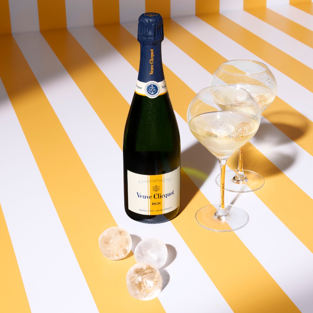 Bouteille de champagne RICH avec des coupes pleines et glaçons sphériques Bouteille de champagne RICH avec des coupes pleines et glaçons sphériques
